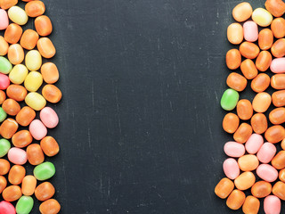 frame of multi-colored candies on a dark background with copy space