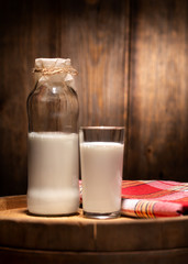 Milk in a glass bottle. Milk poured into a glass. Fresh milk in a bottle and a glass standing on a wooden table.