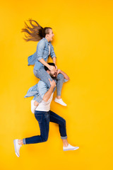 Fototapeta na wymiar Vertical top view above high angle flat lay flatlay lie full length body size view concept of cheerful spouses flying guy carrying girl isolated on bright vivid shine vibrant yellow color background