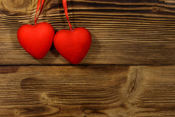 Two red hearts hanging over wooden background