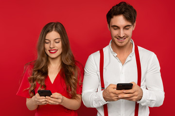 elegant smiling couple using smartphones, use modern technologies for posting new photos in social...