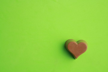 Chocolate bonbon with heart shape in color background