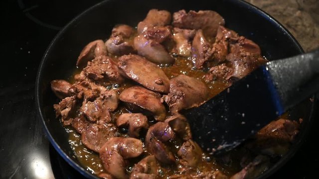 Homemade chicken liver with sauce fried in a frying pan and stirred with a spatula