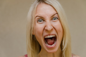 Portrait of a girl who screams, angry. Manifestation of emotions by a woman