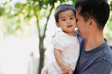 Asian daddy is playing and kissing to his baby boy with love and baby is smiling with fully happy moment, concept of love and relation in asian family lifestyle.