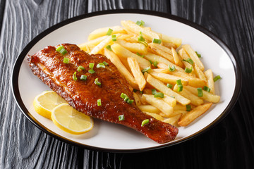 Whole cooked Sebastes fish with french fries and lemon on a plate in a plate on the table. horizontal