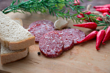 Smoked sausage sliced into pieces, slices of garlic and red chili peppers on a dark background. Not a healthy diet. The concept of cooking.