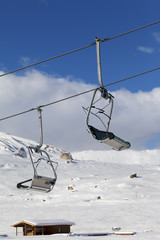 Fototapeta na wymiar Snowy slope, ski-lift and blue sky with clouds at sunny winter day