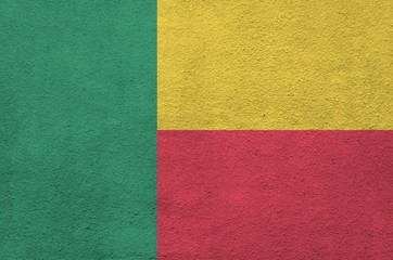 Benin flag depicted in bright paint colors on old relief plastering wall. Textured banner on rough...