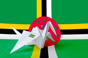 Dominica flag depicted on paper origami crane wing. Handmade arts concept