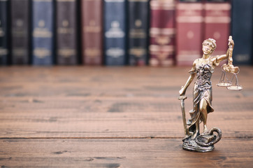 Scales of Justice, Justitia, Lady Justice and Law books in the background.