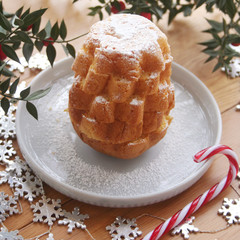 Italian Pandoro sweet cake cut in to shape star on a plate on wooden table with Butcher's broom branches
