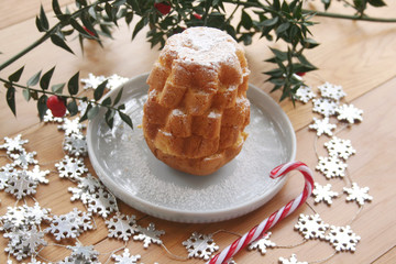 Italian Pandoro sweet cake cut in to shape star on a plate on wooden table with Butcher's broom branches
