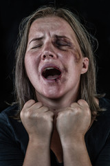 Portrait of a young woman victim of domestic violence and abuse having nervous breakdown screaming