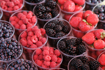 berries in plastic glasses. Fresh strawberries, raspberries, blackberries, blueberries in takeaway cups. market.