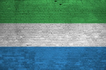 Sierra Leone flag depicted in paint colors on old brick wall. Textured banner on big brick wall...