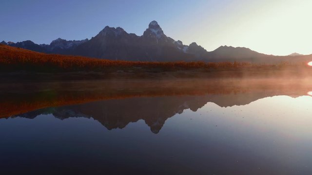 Morning view of fog over a lake with Mt. Ushba mountain in Caucasus, Georgia, pan right