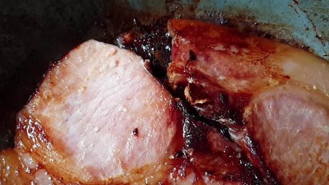 Slow motion pan of pork chops meat in cast iron frying pan with olive oil for food presentations, almost done and ready to be served.