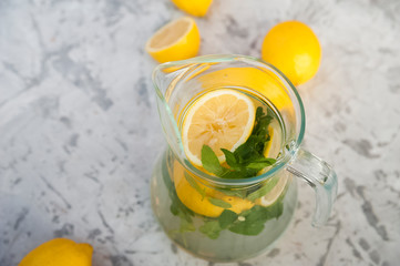 Homemade lemonade on a light background concept. Lemons, glasses, mint, jug and copy space. Summer refreshing drink lemonade.