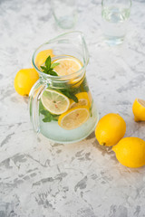 Homemade lemonade on a light background concept. Lemons, glasses, mint, jug and copy space. Summer refreshing drink lemonade.