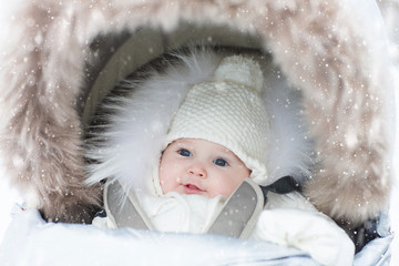 Baby in stroller in winter snow. Kid in pram.