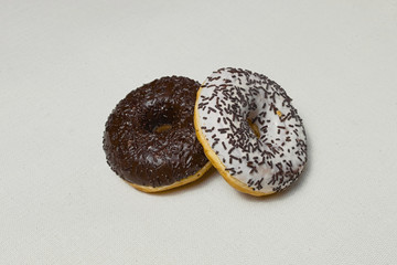  Donuts with black and white icing and chocolate sprinkles lie on a white woven napkin.