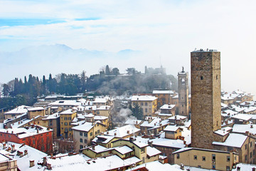 Aerial view of Bergamo old town with snow-covered roofs and ancient tower, winter panorama..