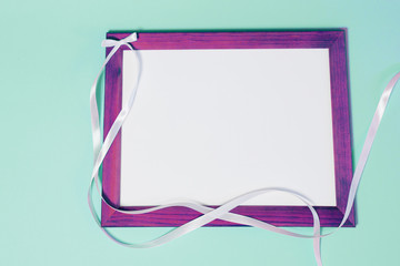 purple frame on turquoise background with white ribbon