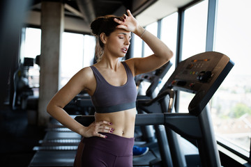 Fototapeta na wymiar Fitness woman. Beautiful young girl in the gym on the treadmill. Fatigue, hand in head, wipes sweat.