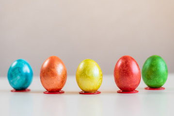 Multi-colored Easter eggs stand in a row on the table.