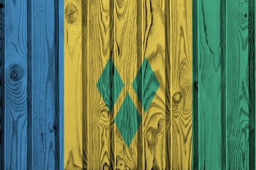 Saint Vincent and the Grenadines flag depicted in bright paint colors on old wooden wall. Textured...