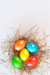 Fototapeta na wymiar Multi-colored Easter eggs lie in a straw, as in a nest.