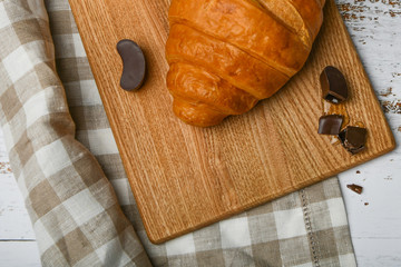 chocolate croissants. the beginning of the morning. A cup of coffee. Fresh french croissant. Coffee cup and fresh baked croissants on a wooden background. View from above.