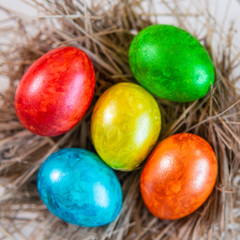 Fototapeta na wymiar Multi-colored Easter eggs lie together on a straw in the form of a nest on a white background. Happy easter