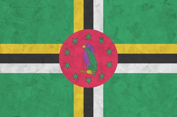 Dominica flag depicted in bright paint colors on old relief plastering wall. Textured banner on...