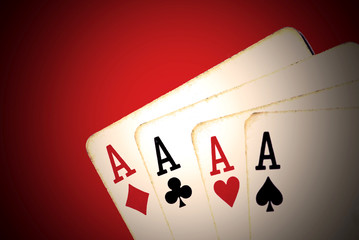 Worn playing cards, four aces on red background