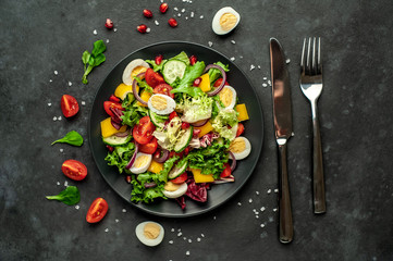 Salad with pomegranate, eggs, tomatoes, fresh cucumbers, onions, sesame and bell pepper, spices on a stone background. Healthly food.