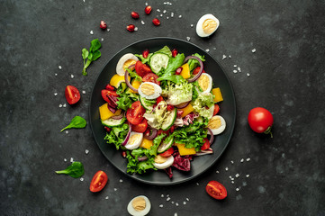 Salad with pomegranate, eggs, tomatoes, fresh cucumbers, onions, sesame and bell pepper, spices on a stone background. Healthly food.