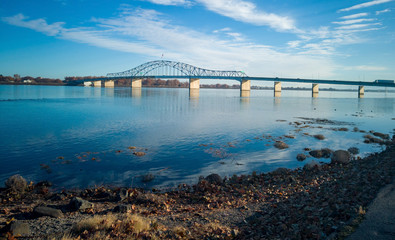 Fototapeta premium Historic blue and white arch truss bridge over the Columbia River with blue skies and clouds on a sunny morning in Kennewick-Pasco Washington