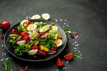 Salad with pomegranate, tomatoes, fresh cucumbers, onions, sesame seeds and cashew nuts, spices on a stone background. Healthy vegetarian food. 