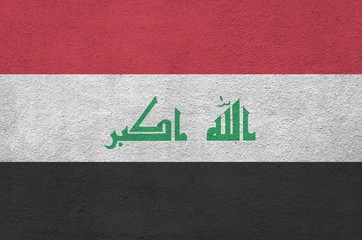 Iraq flag depicted in bright paint colors on old relief plastering wall. Textured banner on rough...
