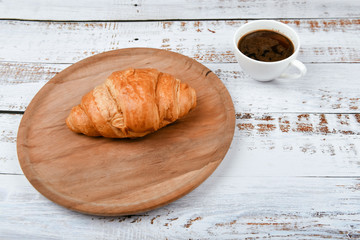 breakfast with croissant. the beginning of the morning. Fresh french croissant. Coffee cup and fresh baked croissants on a wooden background. View from above. Morning breakfast with croissant and coff