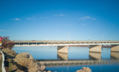 Historic blue and white arch truss bridge over the Columbia River with blue skies and clouds on a sunny morning in Kennewick-Pasco Washington