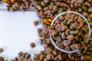 Top view of colorful dry pet food in a white ceramic bowl
