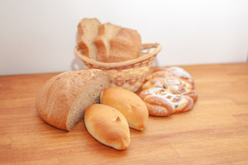 Two patties and a sliced loaf of bread on a wooden table