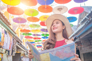Smiling woman traveler in chiangmai market landmark thailand holding world map on holiday, relaxation concept, travel concept