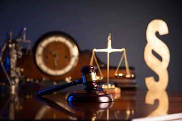 Law concept. Judge’s gavel, scale and old clock on dark background.