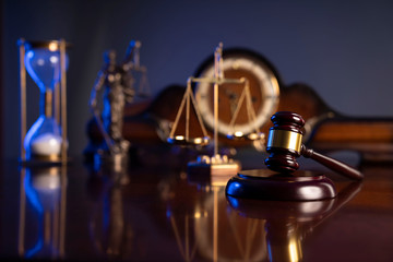 Law concept. Judge’s gavel, scale and old clock on dark background.