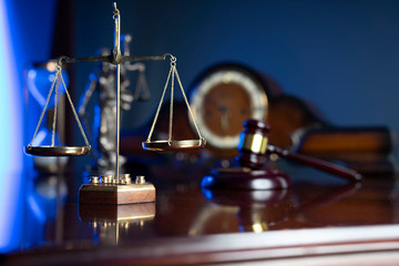 Law concept. Judge’s gavel, scale and old clock on dark background.