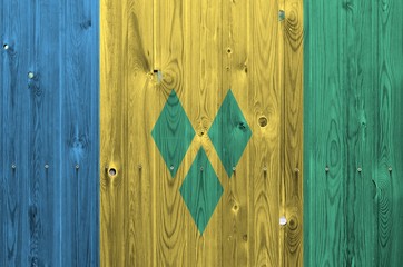 Saint Vincent and the Grenadines flag depicted in bright paint colors on old wooden wall. Textured...